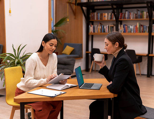 Career Coach NJ meeting with a client at a table, reviewing notes and discussing career goals in a modern office setting