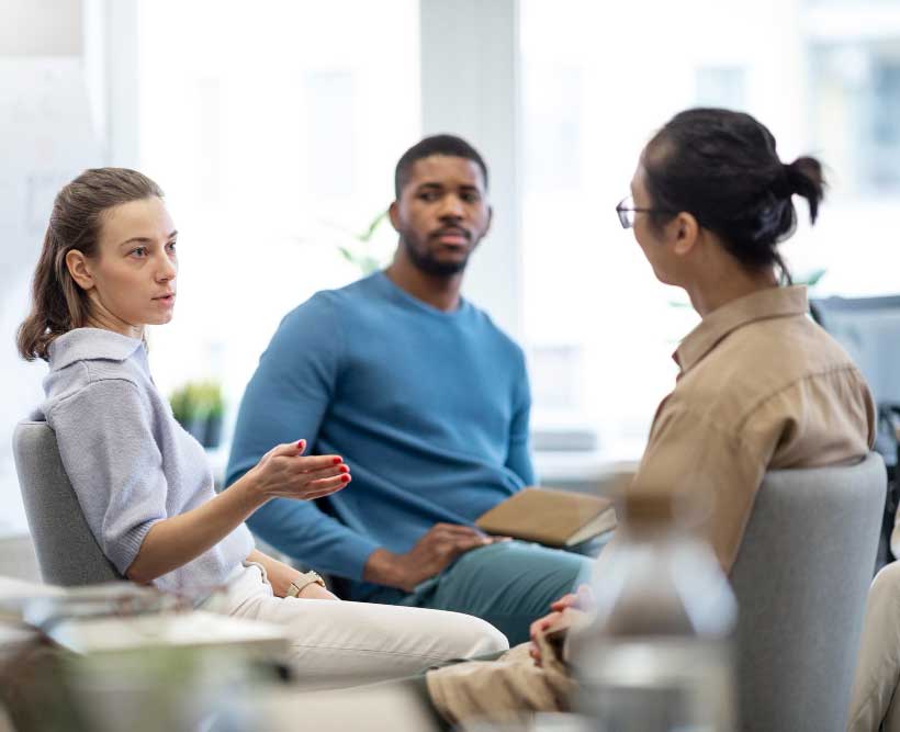 Transition Coach facilitating a group coaching session with individuals discussing personal challenges and growth in a supportive environment